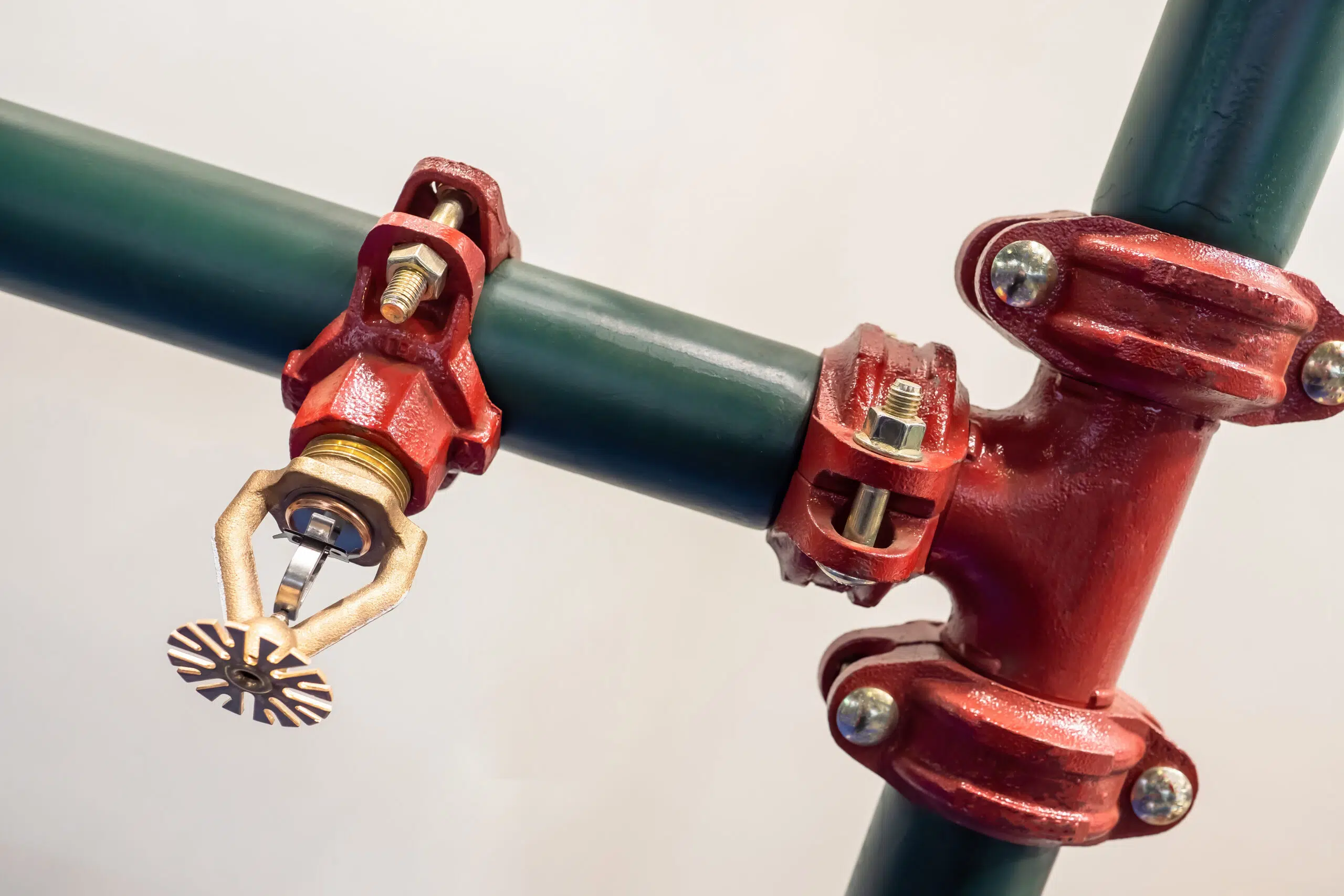 Red fire sprinkler on green pipe